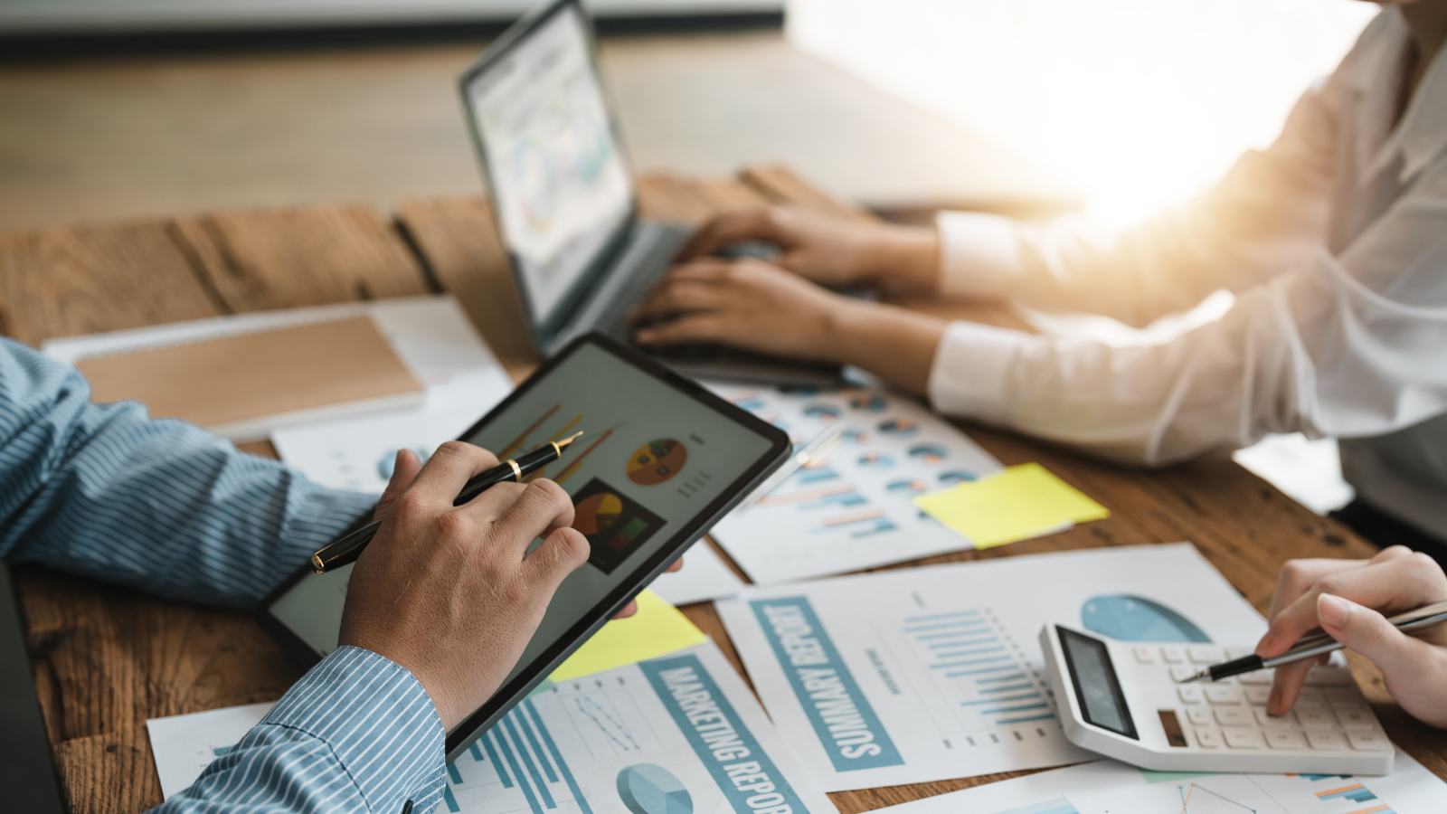 Naperville tax accountant reviewing financial charts on a tablet while working with a team on tax reports, spreadsheets, and calculations